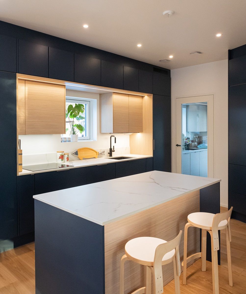 Evenly spaced spotlights on the ceiling also bring light to the kitchen island. The front edge of the island is illuminated downwards by a LED strip in an aluminium profile.